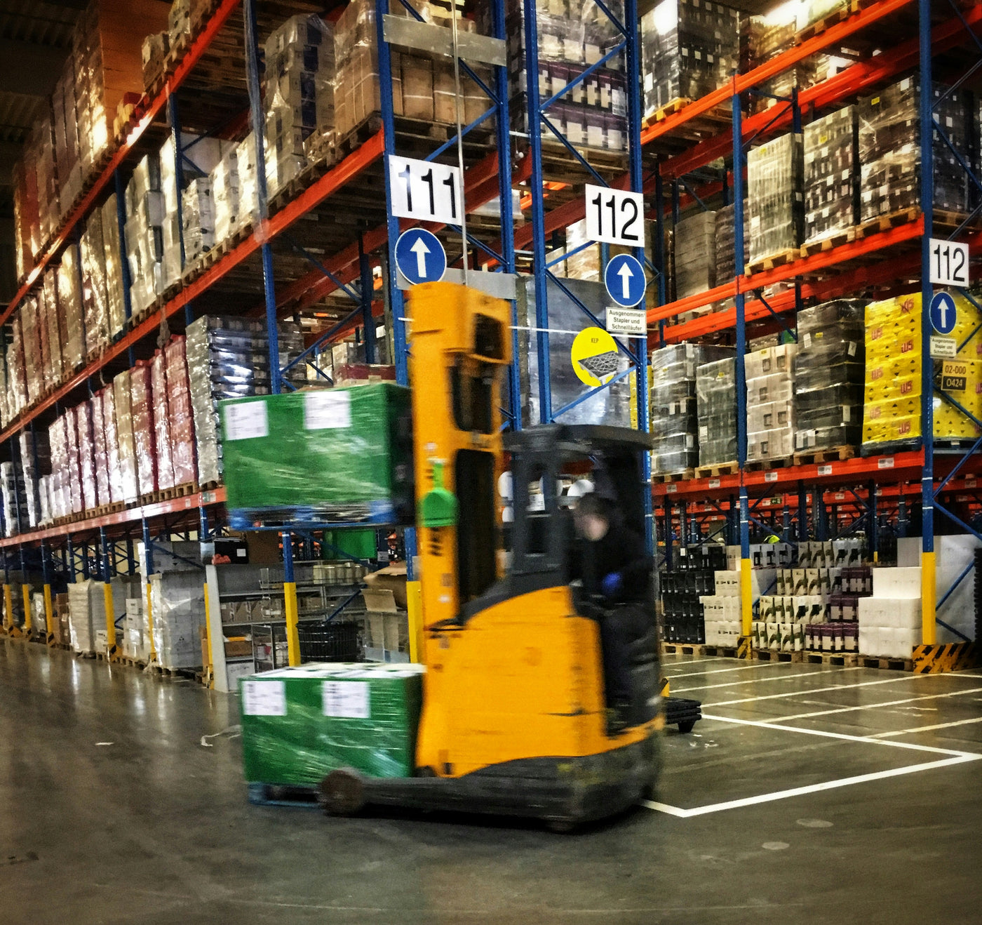 A forklift driving through a factory filled with factory shelving and racking